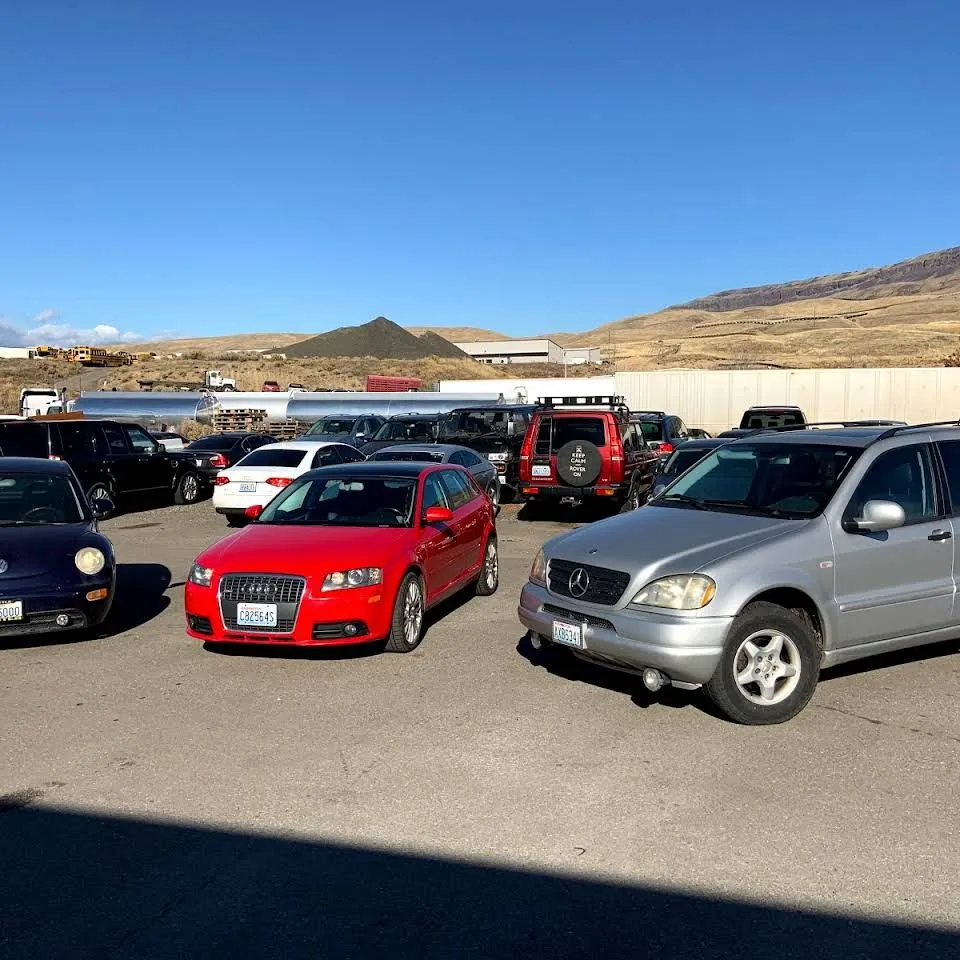 Customer cars on the lot at Erik's under a clear sky, including a red Audi A3 and a silver Mercedes-Benz ML.