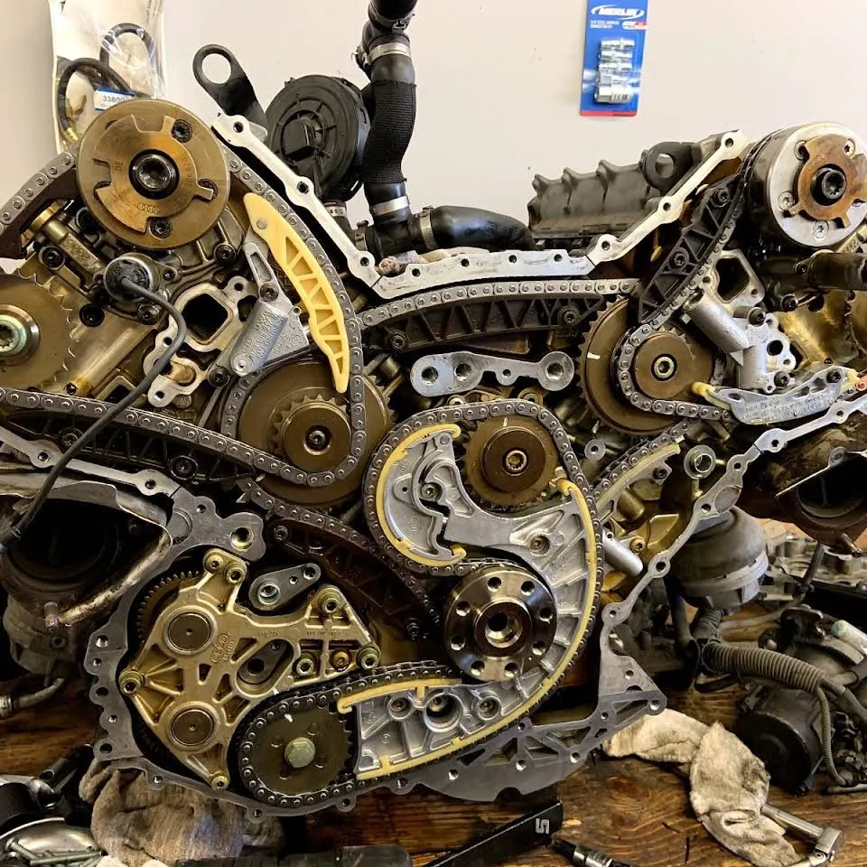 A V8 timing chain drive laid open on the workbench at Erik's, with the Audi rings cast into a camshaft adjuster.